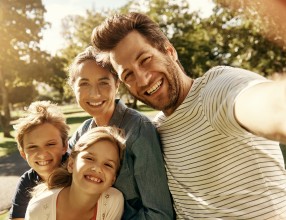 Mann macht ein Selfie von sich, seiner Frau, Tochter und Sohn